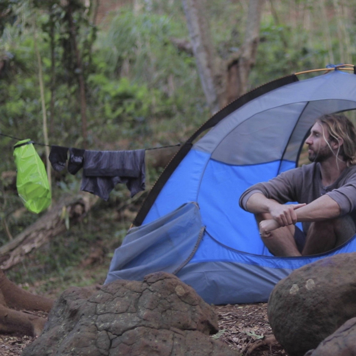 Man in tent with drying clothes from a Scrubba MINI wash bag